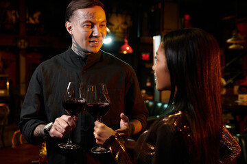 A young couple shares a joyful moment over glasses of wine at a lively bar.
