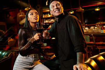 A young multicultural couple shares a memorable evening at a lively bar, savoring drinks.