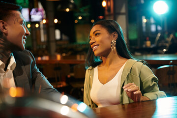 A vibrant young couple enjoying their evening out, exchanging smiles and laughter at a bar.