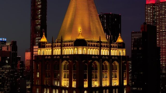 Illuminated facade and spire of the top of New York Life Building skyscraper at night, Madison Avenue in Rose Hill and NoMad neighborhoods of Manhattan