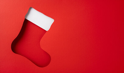 A festive cutout shaped like a Christmas stocking on a vibrant red background, evoking holiday...