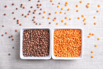 Dried red and brown lentils in square shaped white bowls on linen. Shelled and unshelled mountain lentils with brown seed coats and orange-red seeds. Also known as Nipper, Masoor dal, Red Chief, etc.