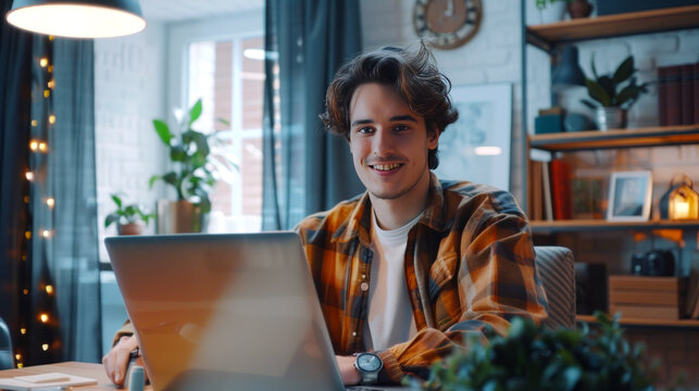 Young focused freelancer working remotely from home office using laptop at night