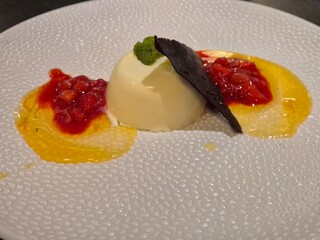 Yellow and red dessert on a white plate close view background