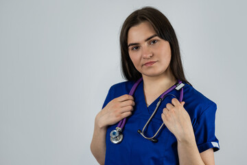 Portrait of woman medical student or doctor in blue uniform with stethoscope isolated on grey