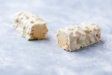 Protein bar in two pieces on wooden background.  Soft focus. Close up. Copy space
