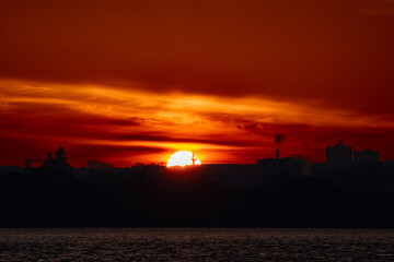 Sun rising behind industrial architecture