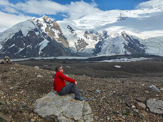 Person sits on a rock, enjoying the stunning mountain landscape and fresh air in a remote alpine area