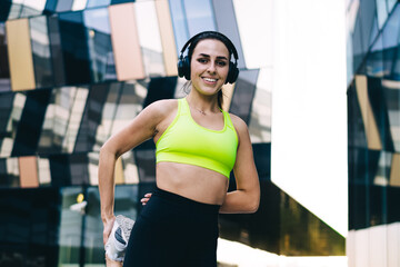 Portrait of cheerful sportswoman training body flexibility during warm up for outside cardio...