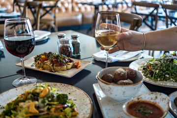 hand holding white wine at dinner table