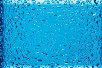 Abstract glass background with clear water droplets on a bright blue surface