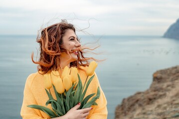 Portrait of a happy woman with hair flying in the wind against the backdrop of mountains and sea....