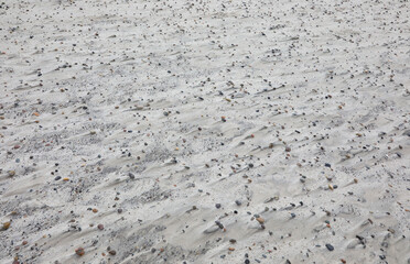 stones on the sandy beach and the mark left by the wind on the grains of sand