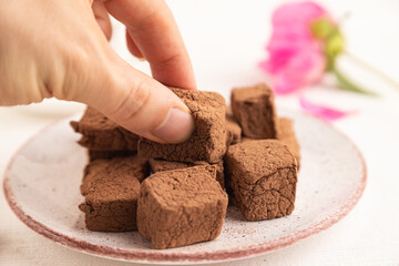 Chocolate marshmallow with cup of coffee with hand on white wooden. side view, selective focus