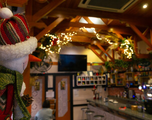 Naklejka premium Christmas decoration in a cafe. Snowman looking to the xmas lights.