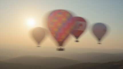 Fototapeta premium Blurred hot air balloons soar over the horizon against a golden sunset, evoking a sense of calm and dreaminess