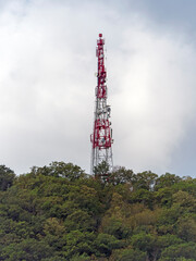Directional antenna array on a red and white communication tower against sky