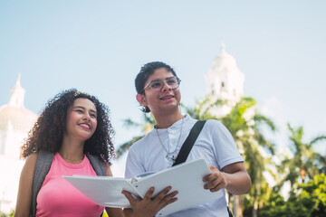 Two latin students discussing outdoors with a notebook in panama city