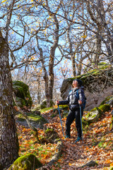 Naklejka premium A woman hiker trekking through La Herrería forest. San Lorenzo de El Escorial. Madrid, Spain.