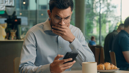 Indian business man guy Arabian businessman male user visitor in cafe hope wish hold mobile phone receive bad news message scam failure cellphone problem sad losing online bet frustrated worried upset