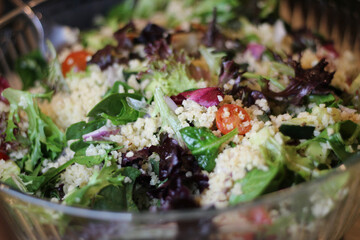 full frame close-up of fresh colorful healthy grain Mediterranean salad with tomatoes cabbage cucumbers in a glass bowl backdrop