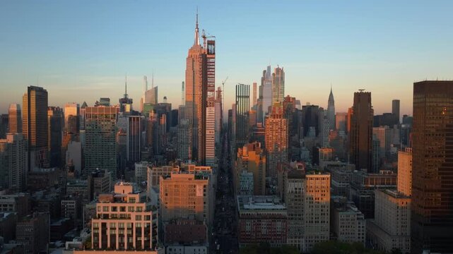 Aerial view of sun setting over Midtown Manhattan and the Empire State Building in New York City. Construction workers on a modern architecture skyscraper