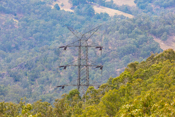 Photograph of a large steel electricity Transmission Tower on a grassy hill in regional Australia.