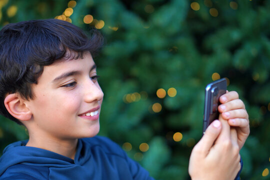 preteen boy making a video call, using his cell phone with a christmas background
