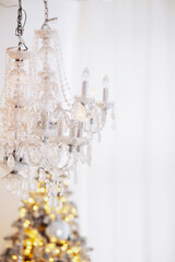 Elegant chandelier adorning a cozy Christmas setting with a tree and decorations