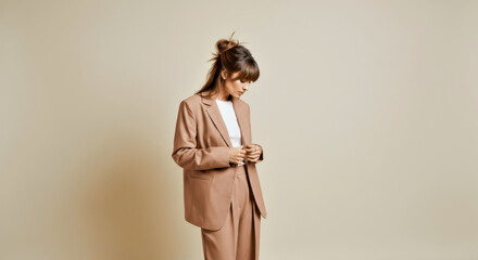 Woman in Brown Blazer with Casual Bun Against Minimalist Background. Scene in mocha mousse color of the year 2025.