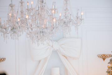 Elegant Christmas decor with a chandelier and festive gift box beneath a tree