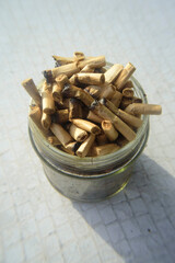 Tarro de cristal lleno de colillas hasta los topes sobre mesa de jardín blanca