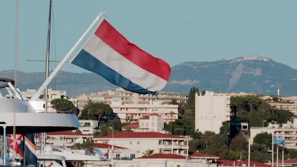 The flag of Netherlands waving on a boat docked in the Port Camille Rayon in Golfe Juan, France - Powered by Adobe