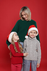 Mother and her little children on red background. Christmas season