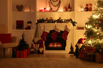 Stylish fireplace, Christmas tree with festive decor and presents indoors