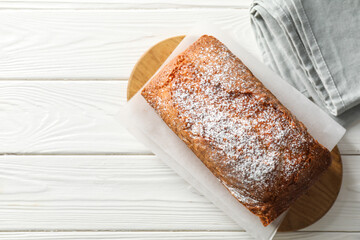 Tasty sponge cake with powdered sugar on white wooden table, top view. Space for text