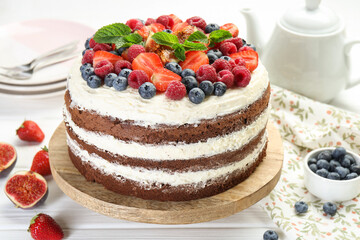 Delicious chocolate sponge cake with berries served on light table, closeup