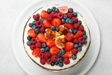 Delicious chocolate sponge cake with berries on light table, top view