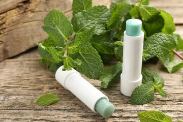 Natural lip balms and mint leaves on wooden background