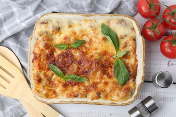 Delicious cooked lasagna with basil served on light wooden table, flat lay