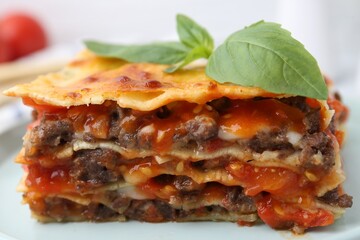 Delicious cooked lasagna with basil on plate, closeup