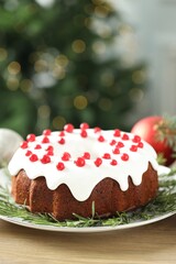 Traditional Christmas cake decorated with red currants and rosemary on wooden table