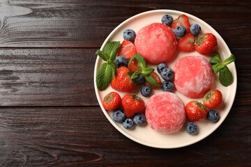 Delicious mochi, strawberries, blueberries and mint on wooden table, top view. Space for text