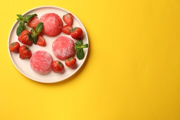 Delicious mochi, strawberries and mint on yellow table, top view. Space for text