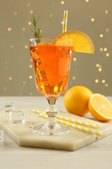 Tasty Christmas cocktail in glass on white wooden table against blurred lights