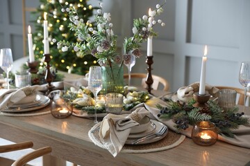 Christmas celebration. Festive table setting with dishware, glasses and decor in room