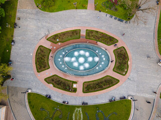 Elegant city square with a modern fountain, surrounded by historic architecture and lush green spaces. A vibrant urban scene perfect for tourism, architecture, and cultural themes.