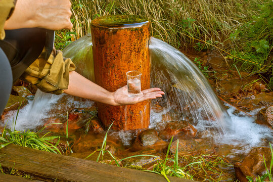 Close-up of female lab technician's hands taking water sample from artesian well. Drinking water quality. Source water is rich in iron. Ferruginous water.