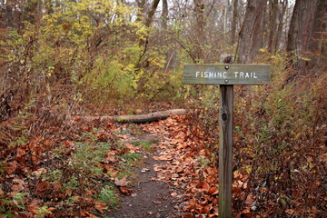 Weathered Engraved Wooden Sign Points Anglers Toward The Fishing Trail