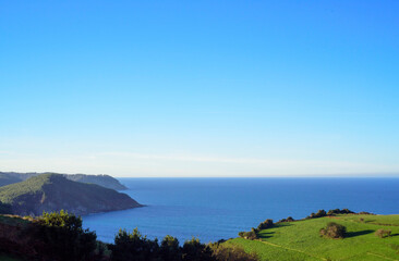 Bahía marina desde praderas verdes de hierba en costa de Asturias